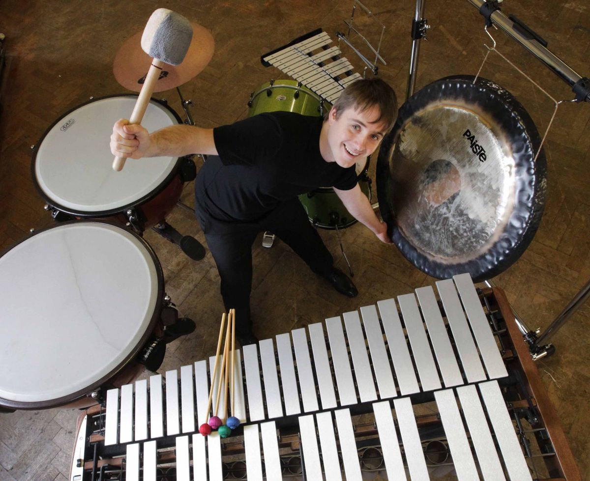 Alex Petcu seen from above, surrounded by drums, a gong and a marimba, holding a large mallet